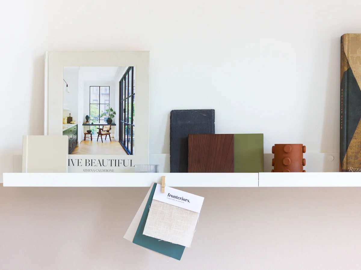 Wood, tile and fabric samples arranged on a shelf beside an interiors book