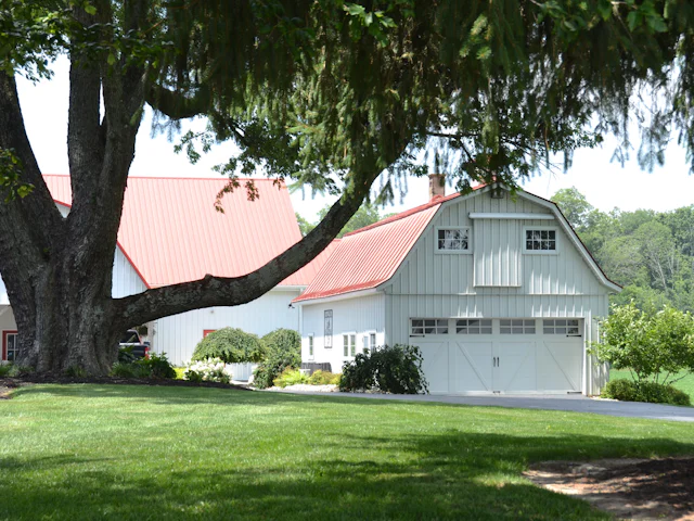Simple white detached garage with a metal roof on a green lawn
