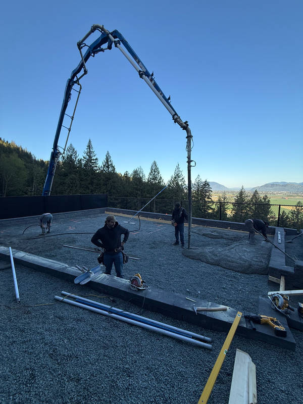 Crew placing concrete from a pump truck boom on a hillside site overlooking the valley